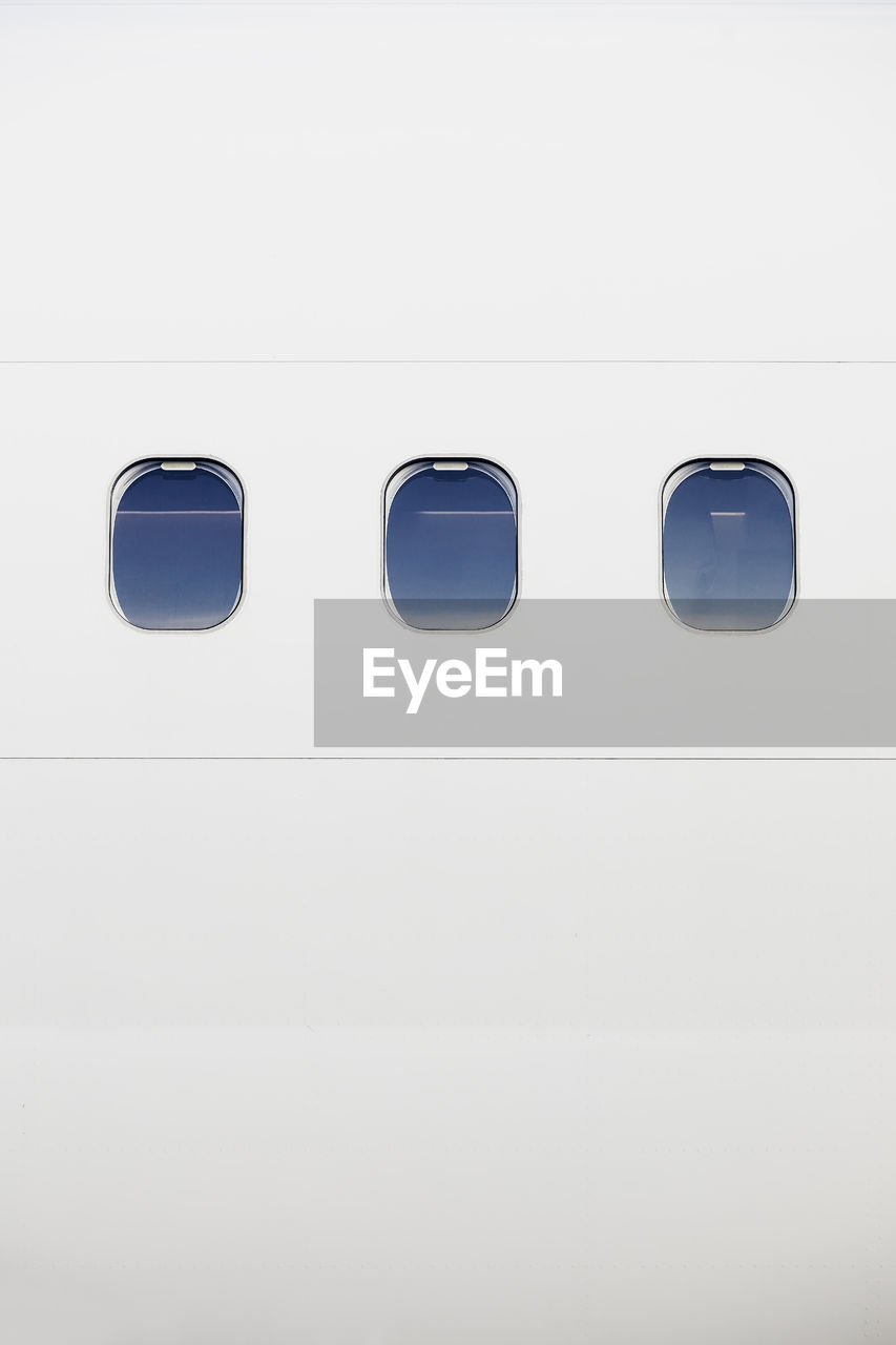 Three windows on fuselage of white airplane. vertical image of plane with copy space.