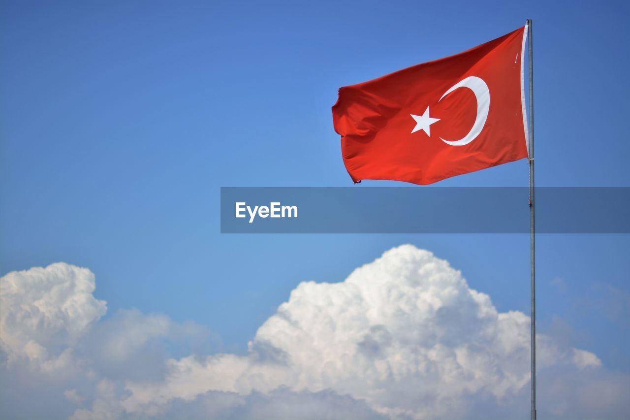 Low angle view of turkish flag fluttering against the sky