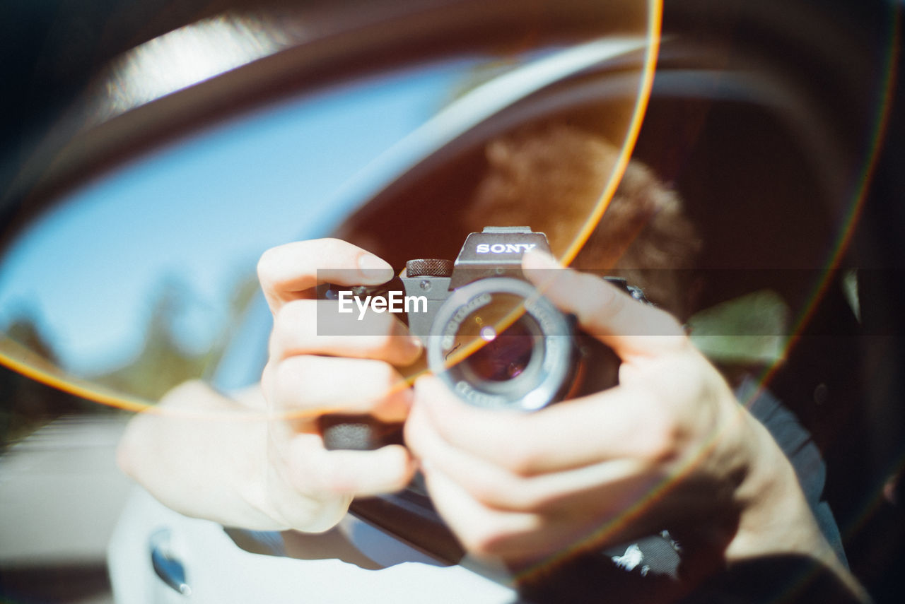 CLOSE-UP OF HAND HOLDING CAMERA