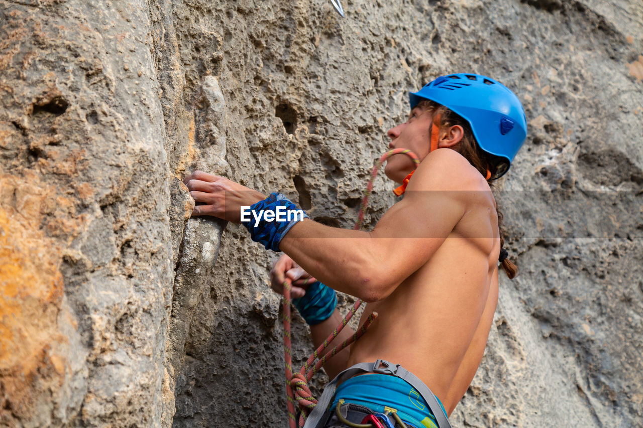 Low angle view of shirtless man rock climbing