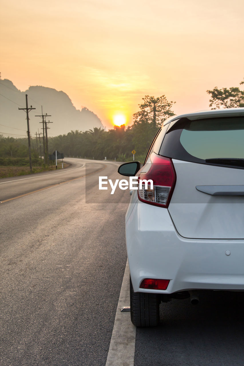 CAR ON ROAD AT SUNSET