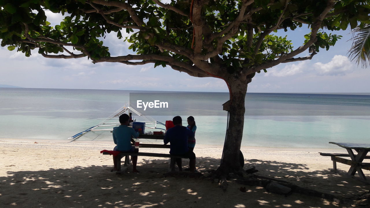 REAR VIEW OF COUPLE STANDING ON BEACH