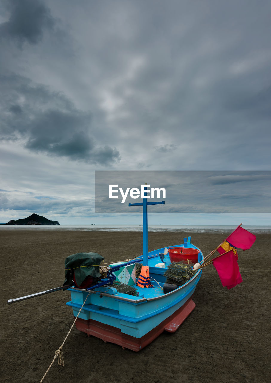 Boat moored on beach against sky