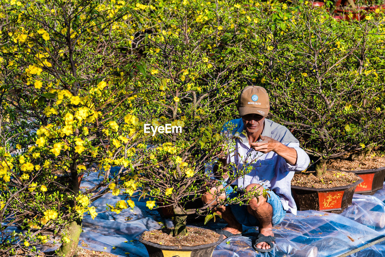 MAN SITTING AGAINST PLANTS AND TREES