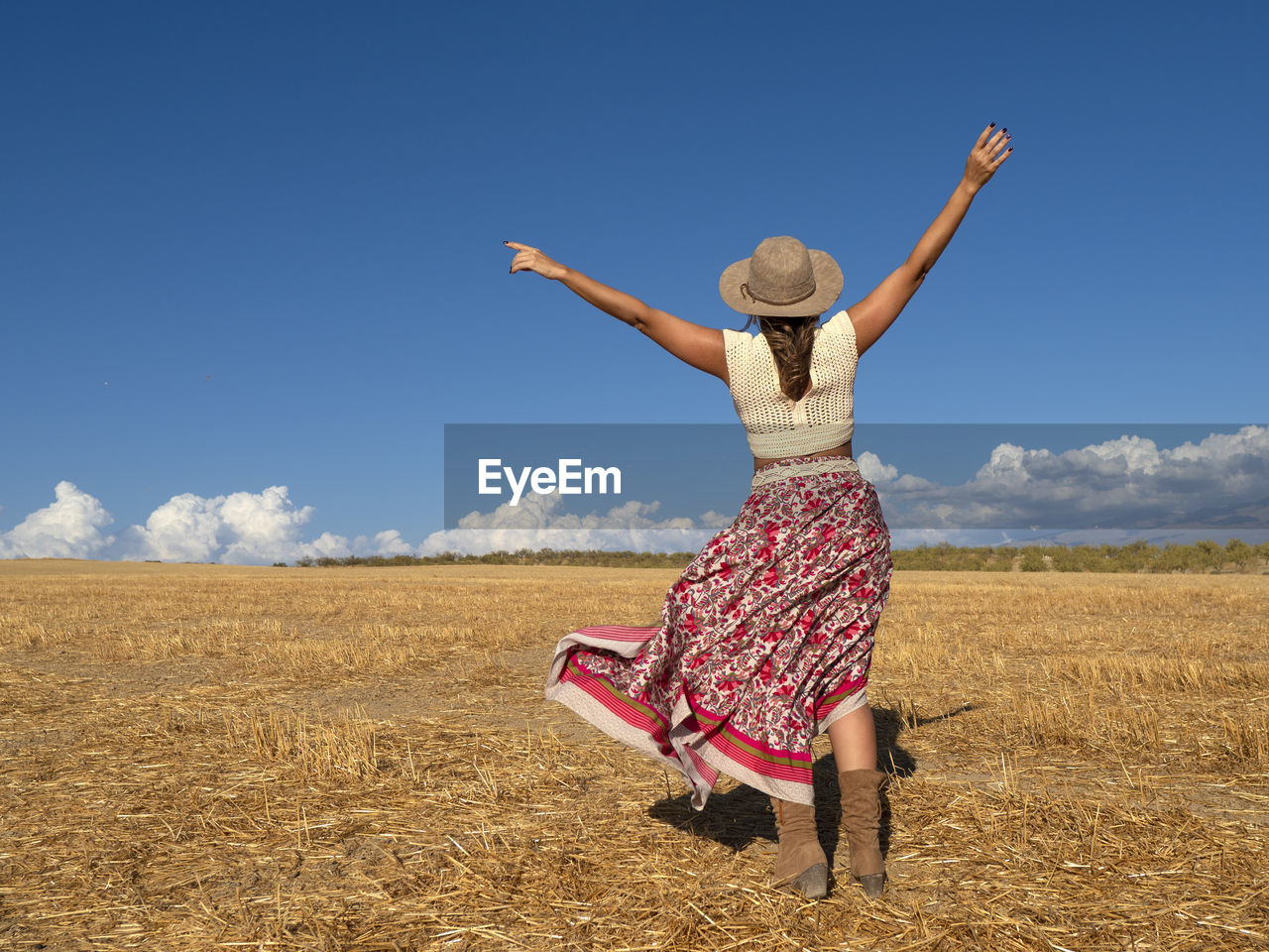 Rear view of woman standing on field against sky