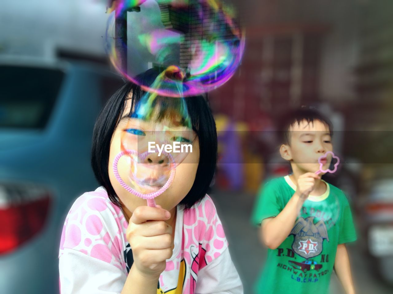 Siblings blowing bubbles outdoors