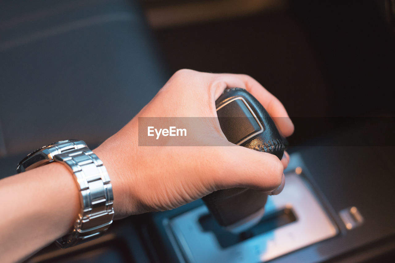 Cropped hand of man holding gearshift in car