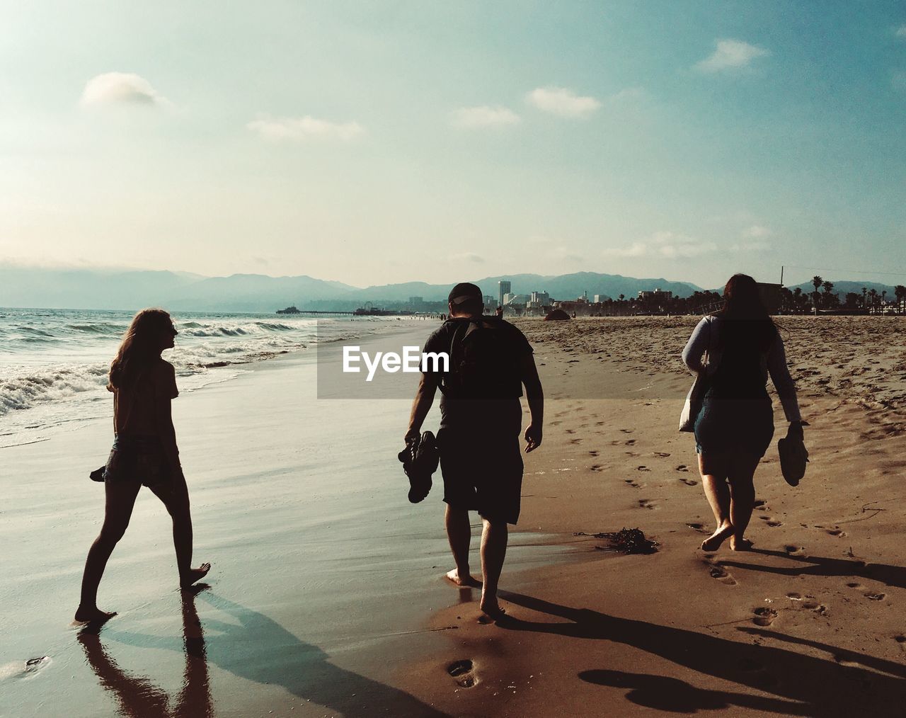 Rear view of people walking on beach