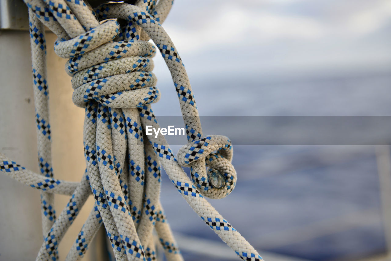 Close-up of rope tied to bollard against sky