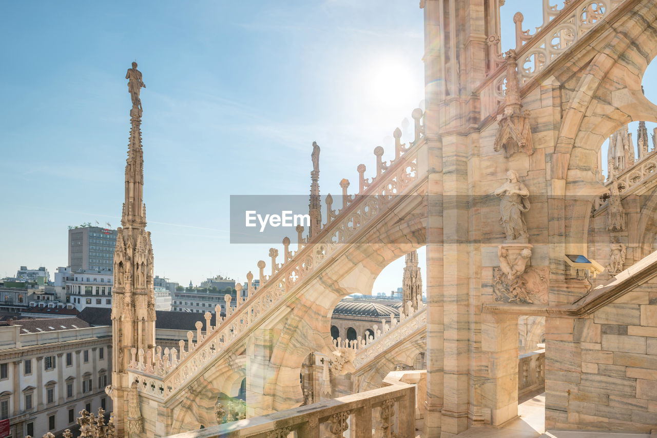 View to spires and statues on roof of duomo through ornate marble fencing. milan, italy