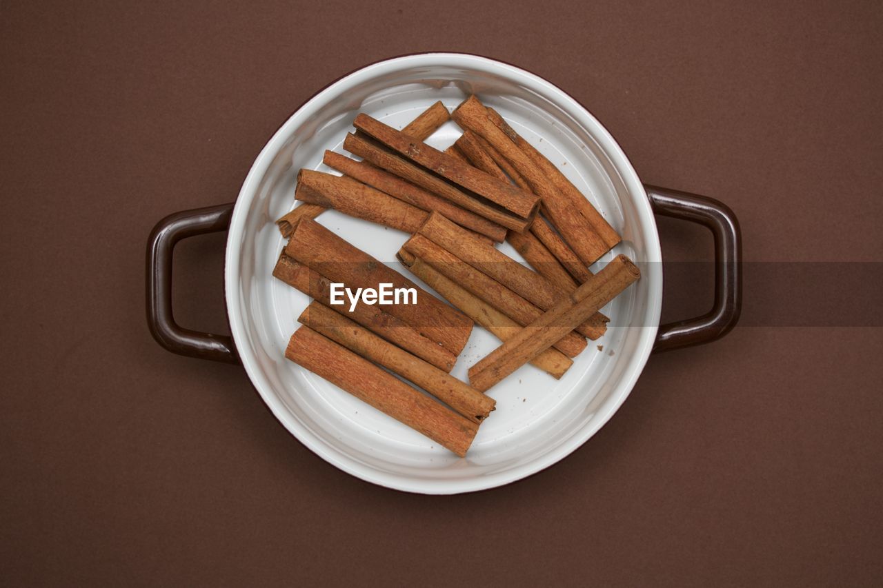 Directly above shot of cinnamon in container on brown background