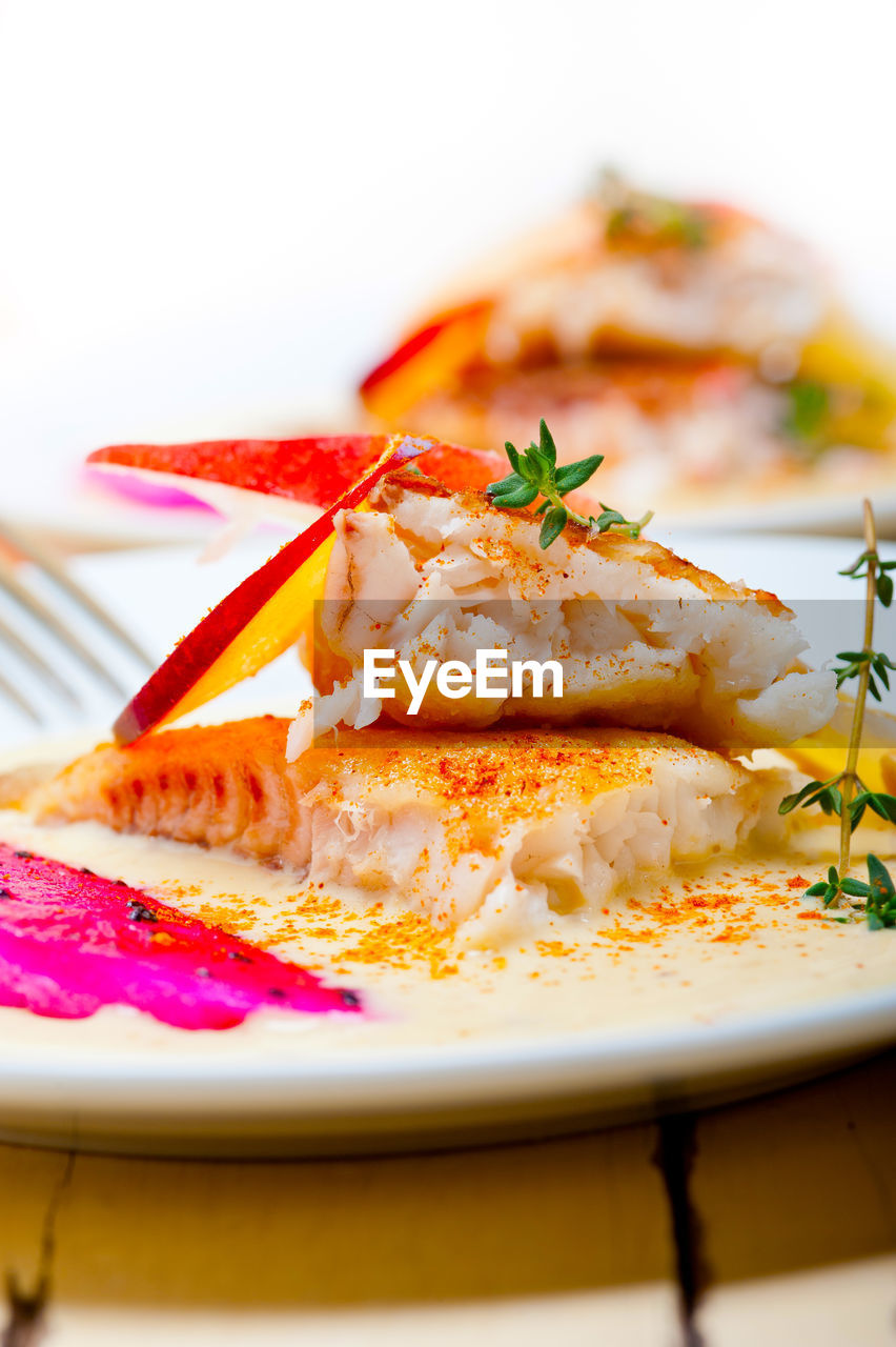 Sea bream orata fillet butter pan fried with fresh peach prune and dragonfruit slices thyme on top