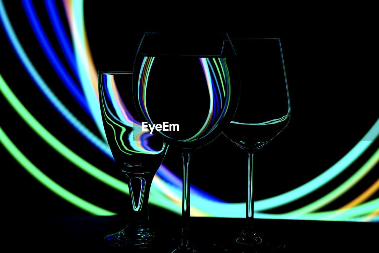 CLOSE-UP OF WINE GLASS AGAINST ILLUMINATED LIGHTS