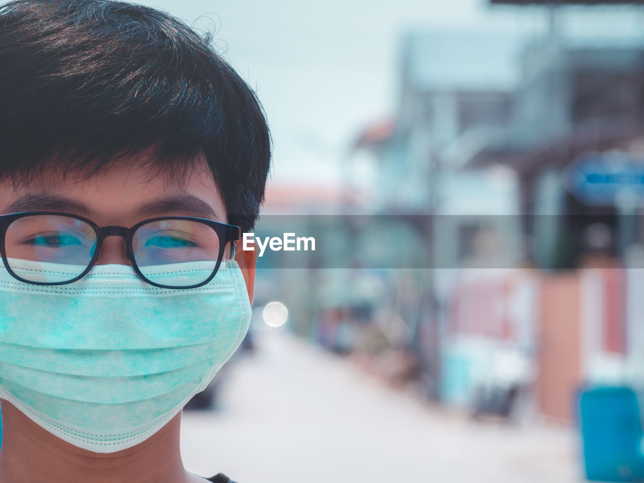 Close-up portrait of boy wearing pollution mask in city