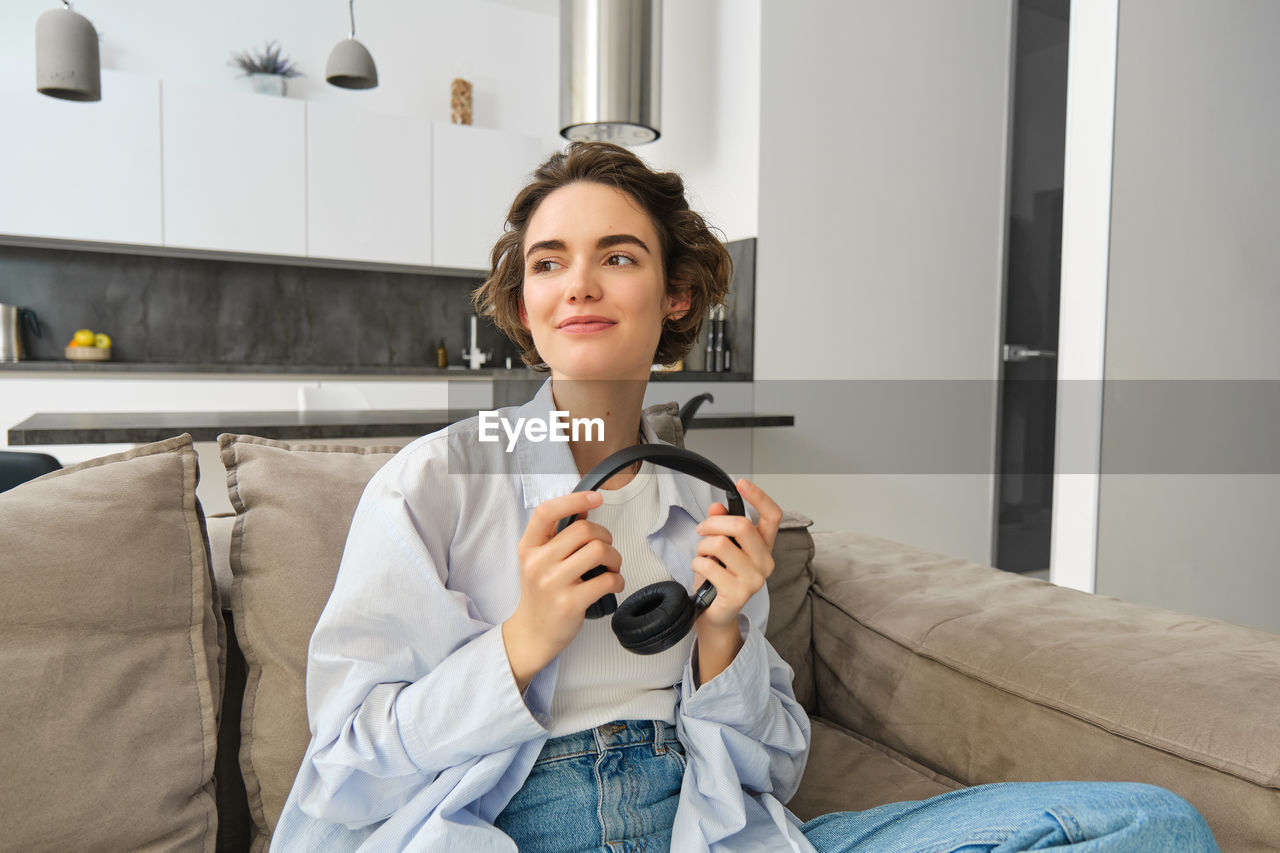 young woman using mobile phone while sitting on sofa at home