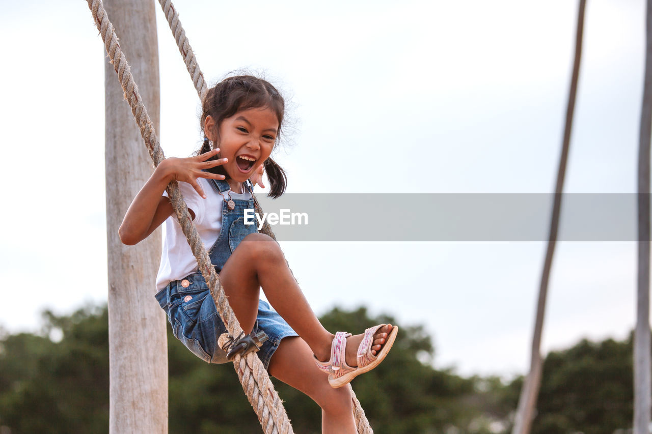 Full length side view of girl swinging at playground