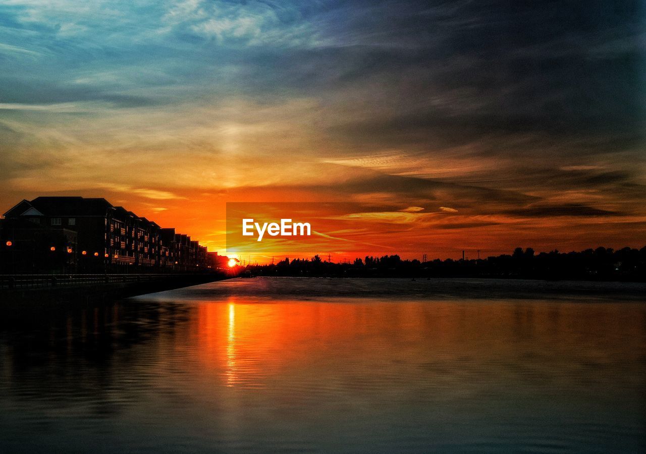 Scenic view of river against cloudy sky at sunset