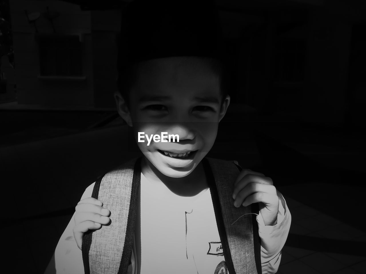 Portrait of boy with backpack standing in darkroom