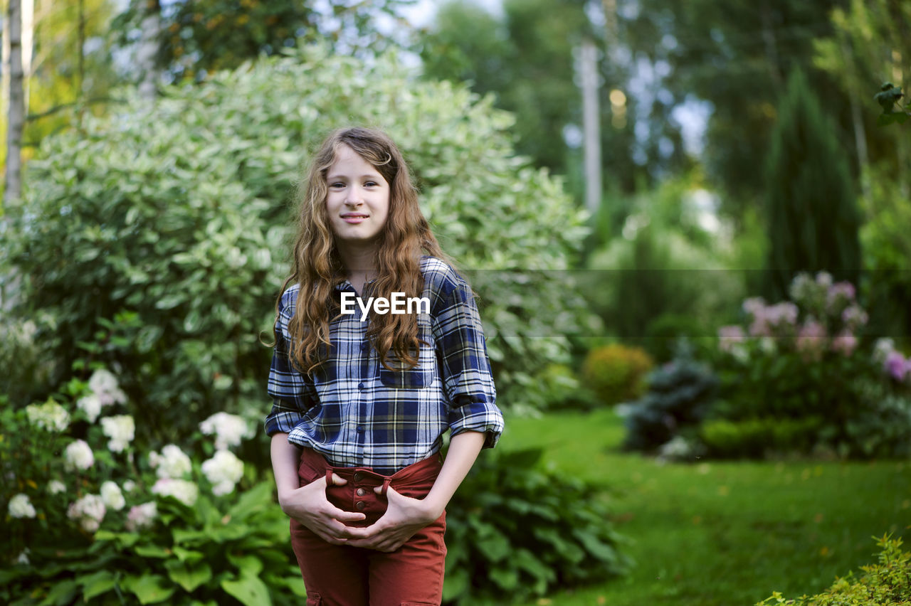 Portrait of young woman standing against plants