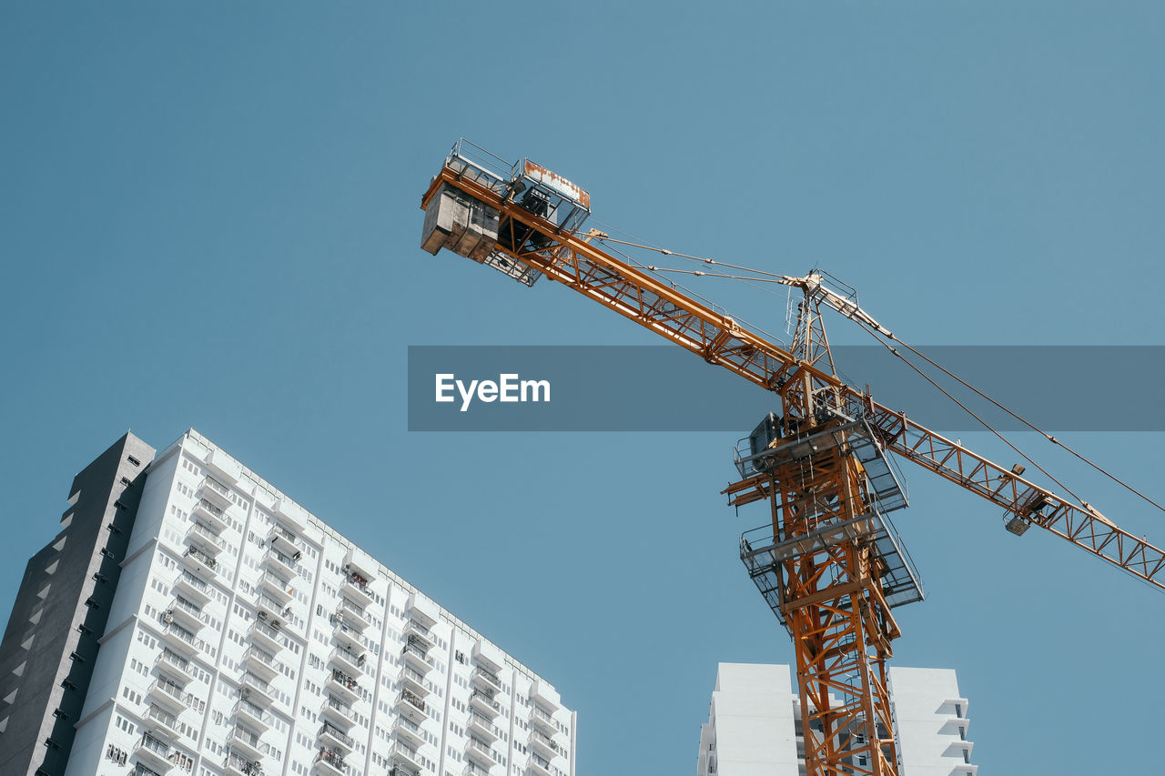 Low angle view of tower crane against blue sky