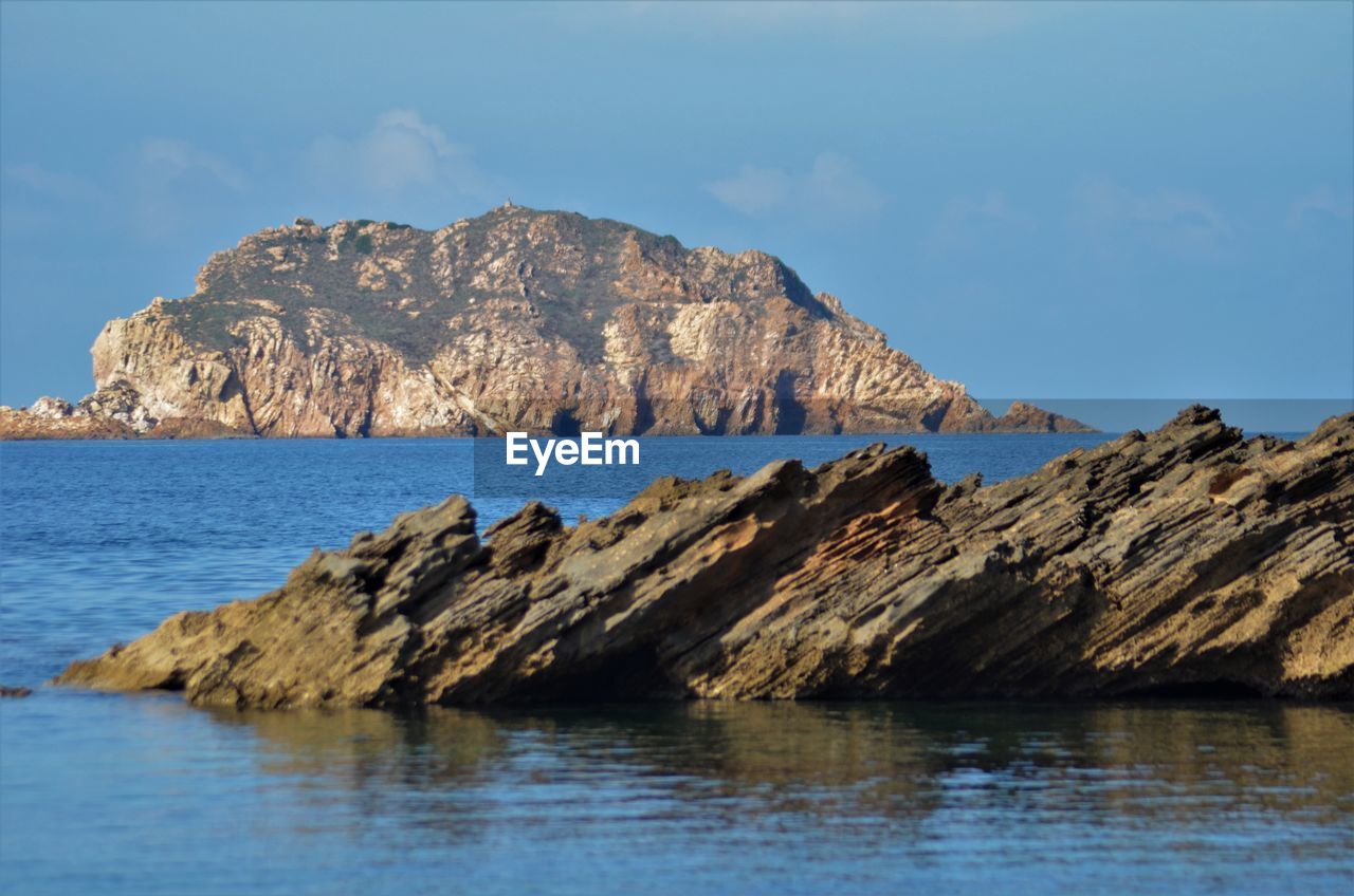 Rock formations by sea against sky