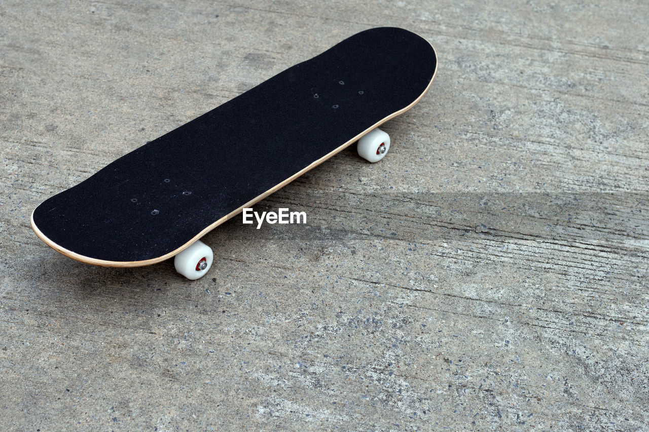 HIGH ANGLE VIEW OF SKATEBOARD ON FLOORING