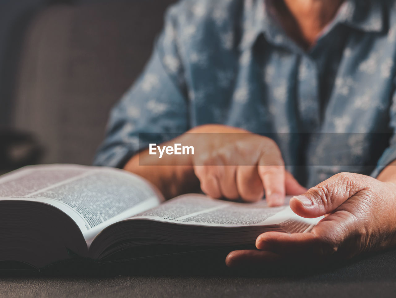 Midsection of person reading book while sitting at table