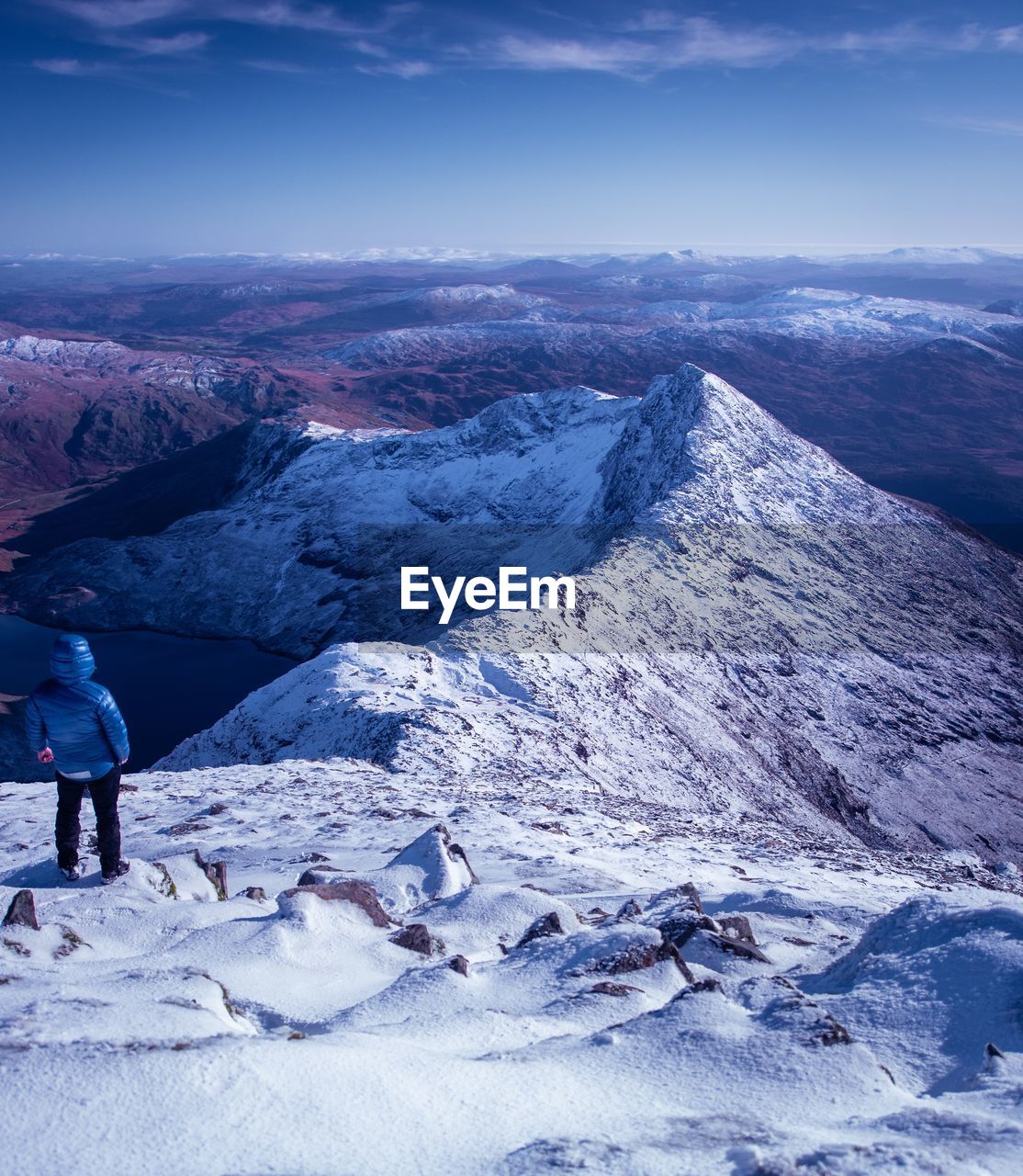 Rear view of man standing on snowcapped mountain