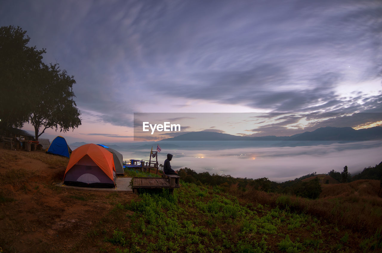 TENTS ON FIELD AGAINST SKY DURING SUNSET