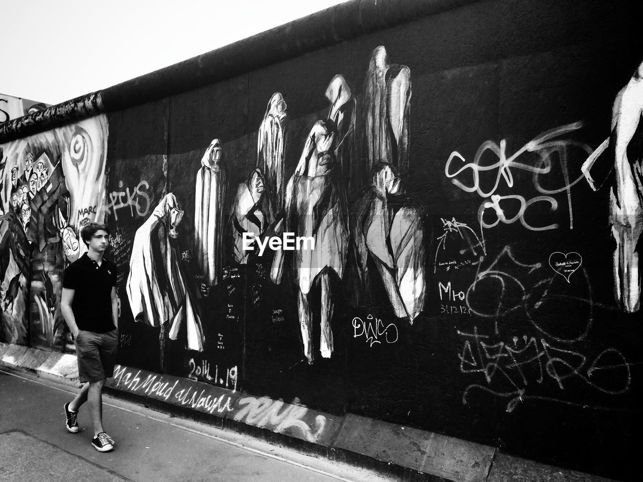 Full length of man walking by graffiti on wall