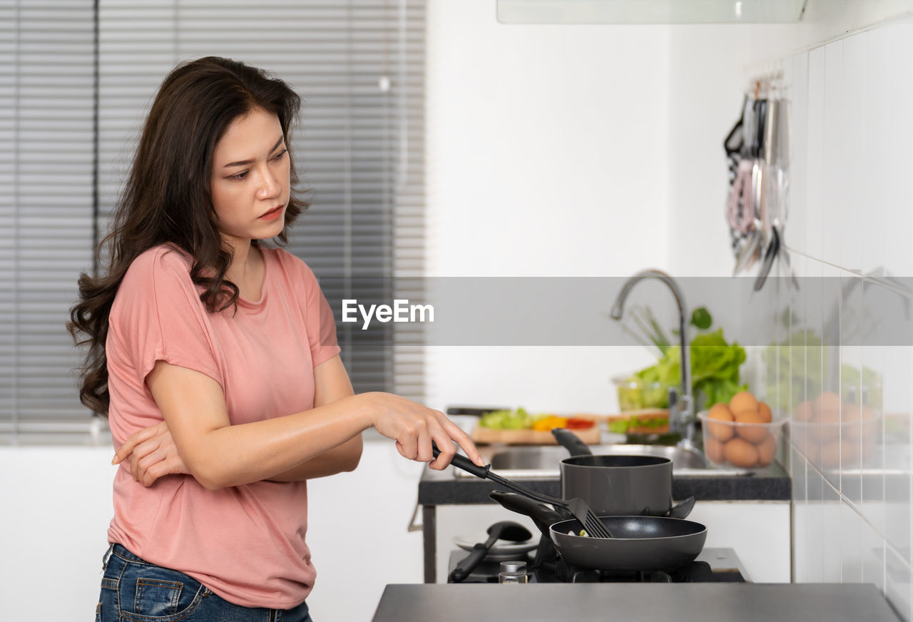 Sad woman preparing food at home