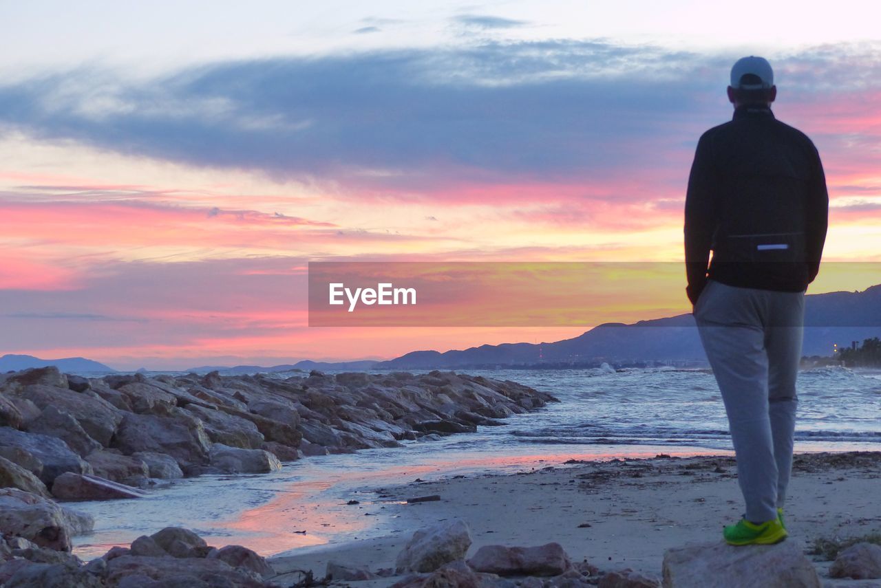 Man standing at beach during sunset