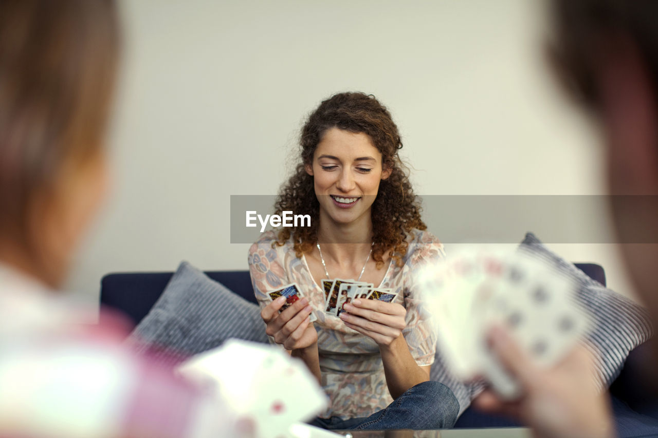 Beautiful woman smiling while playing cards with friends