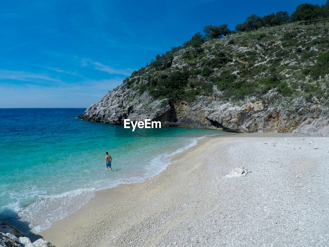 High angle view of shirtless man standing in sea against sky