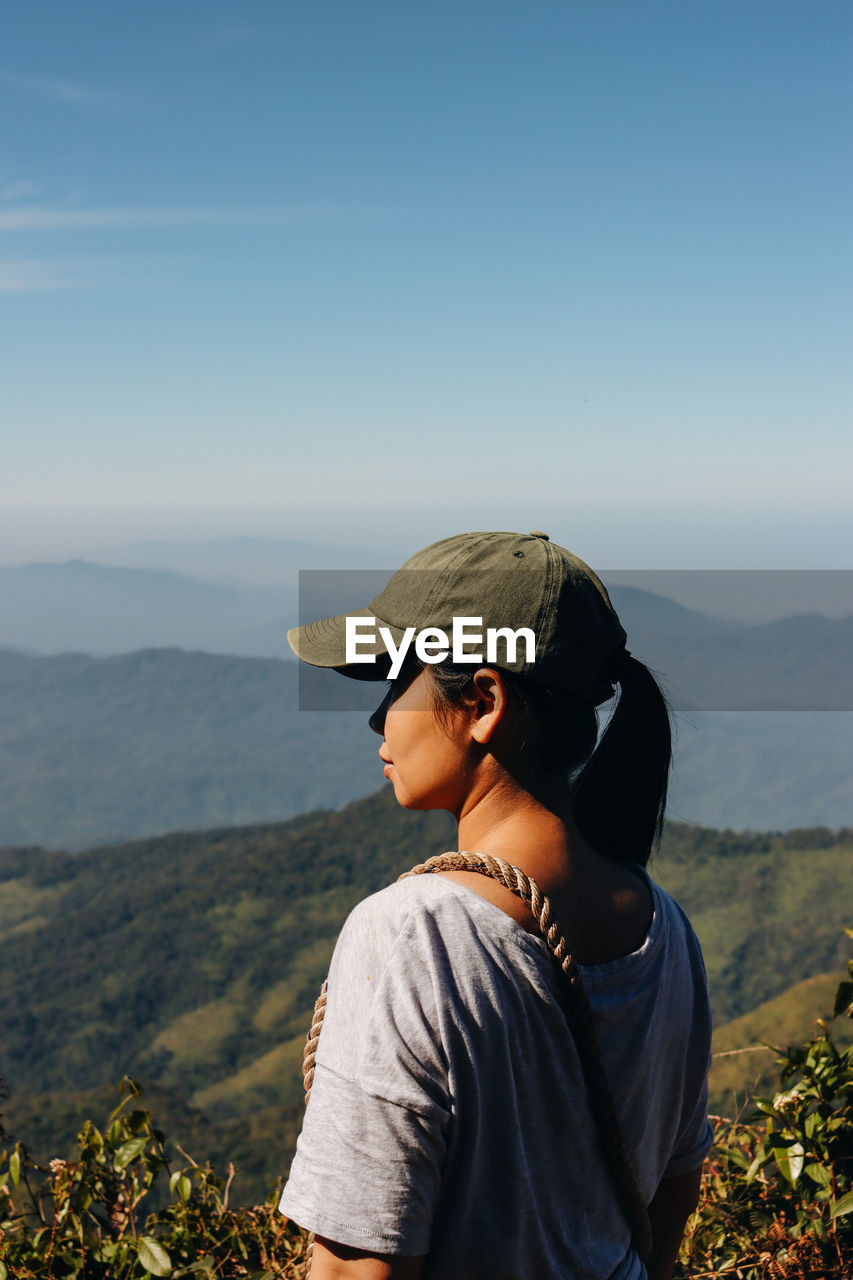 A woman standing on top of the mountain overlooking the mountain range