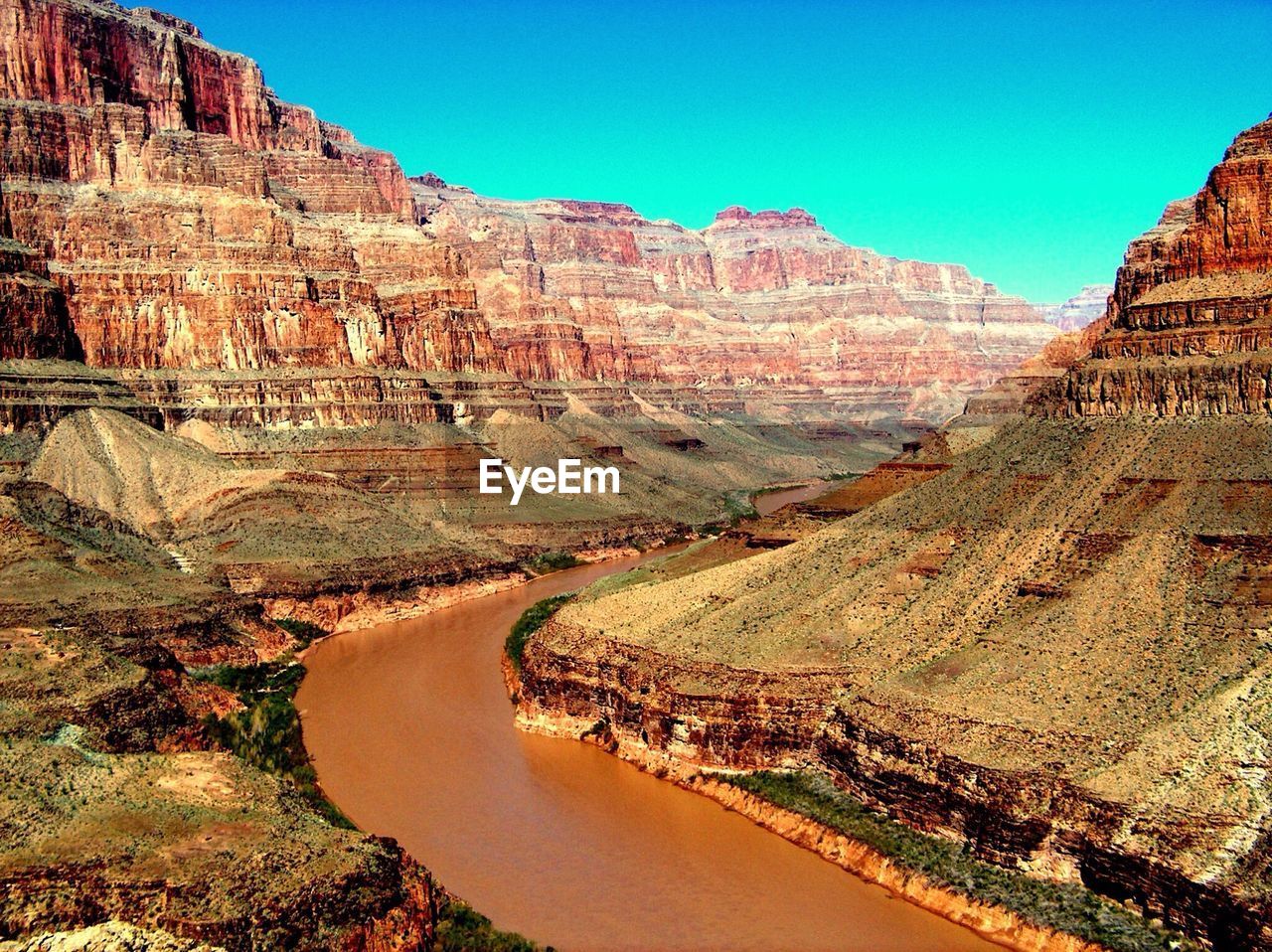 Scenic view of river flowing along side rocky mountains