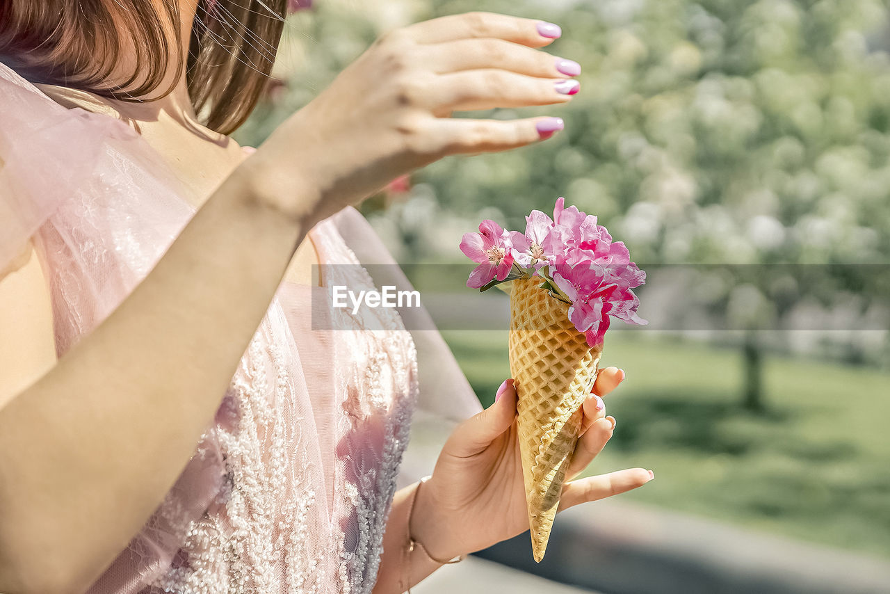 Flowers in a waffle cone in a woman's hand. the flowering of fruit trees in the garden