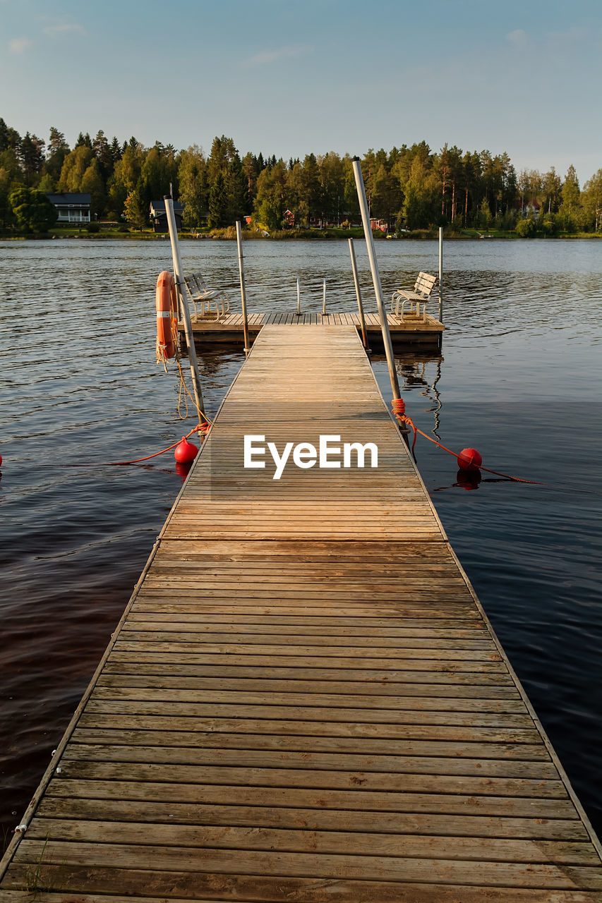 A pier has two wooden benches for the swimmers by a lake at the rural finland. 