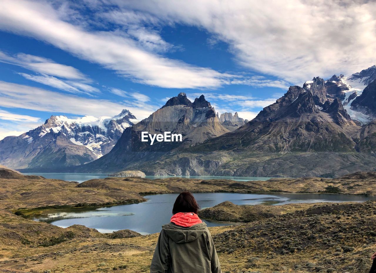 Rear view of woman looking at lake and snowcapped mountain against sky