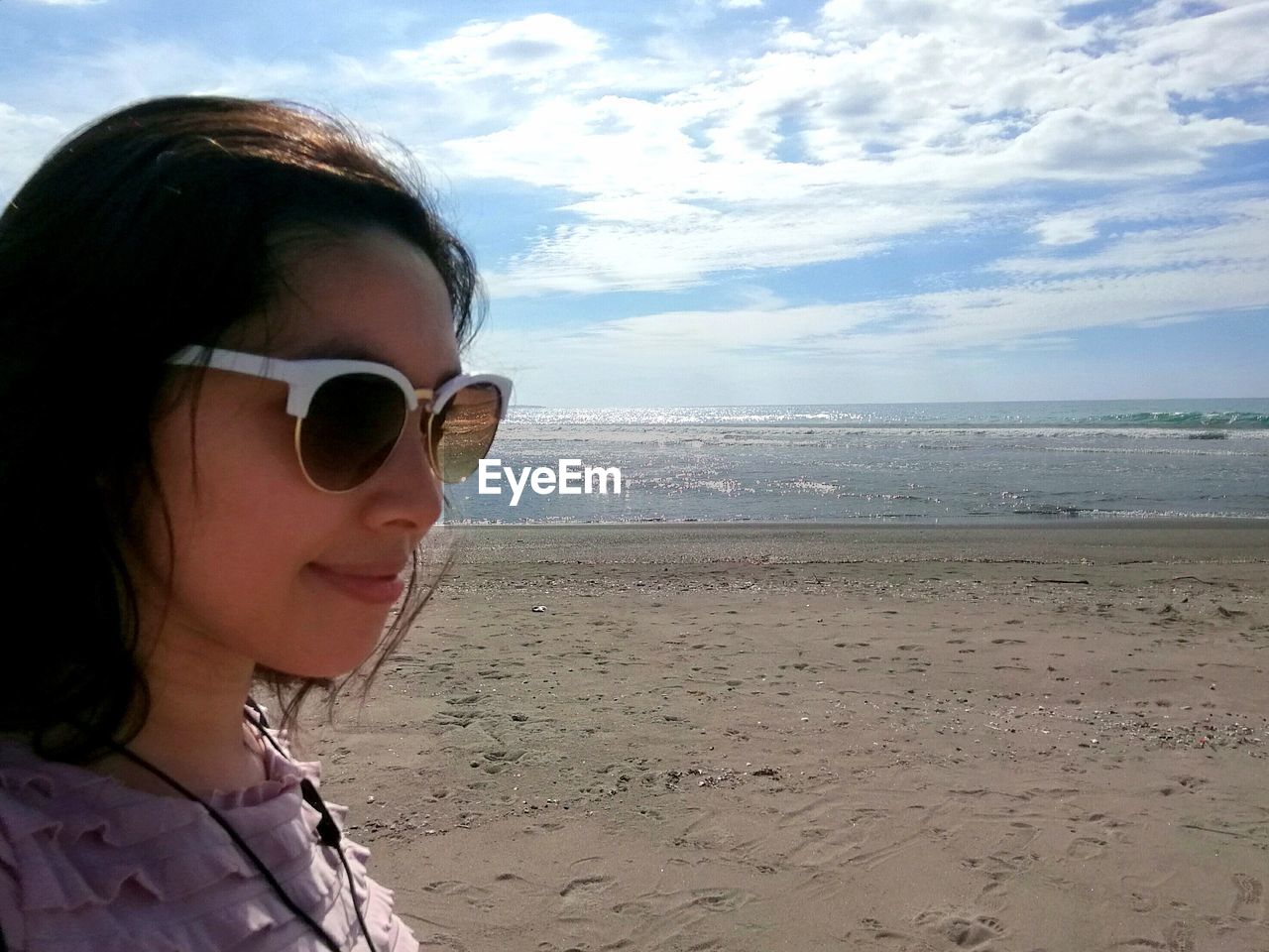 Close-up of smiling young woman wearing sunglasses against sea