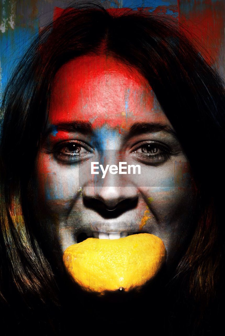 Woman with painted face eating lemon