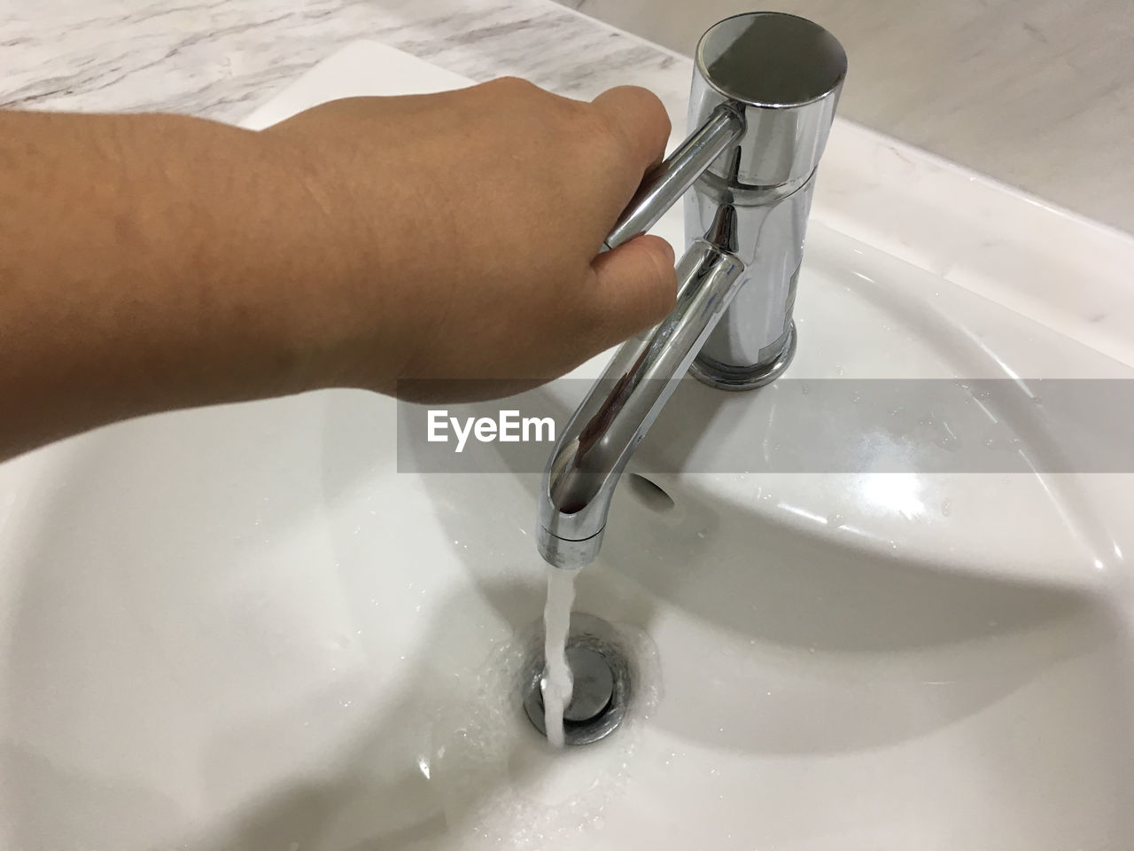 Cropped hand using faucet in bathroom