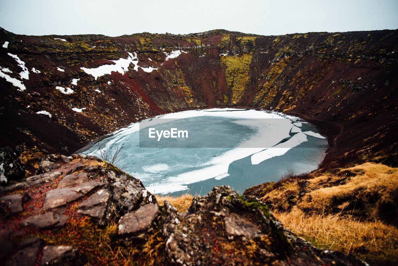 Scenic view of frozen lake by volcanic mountain against clear sky