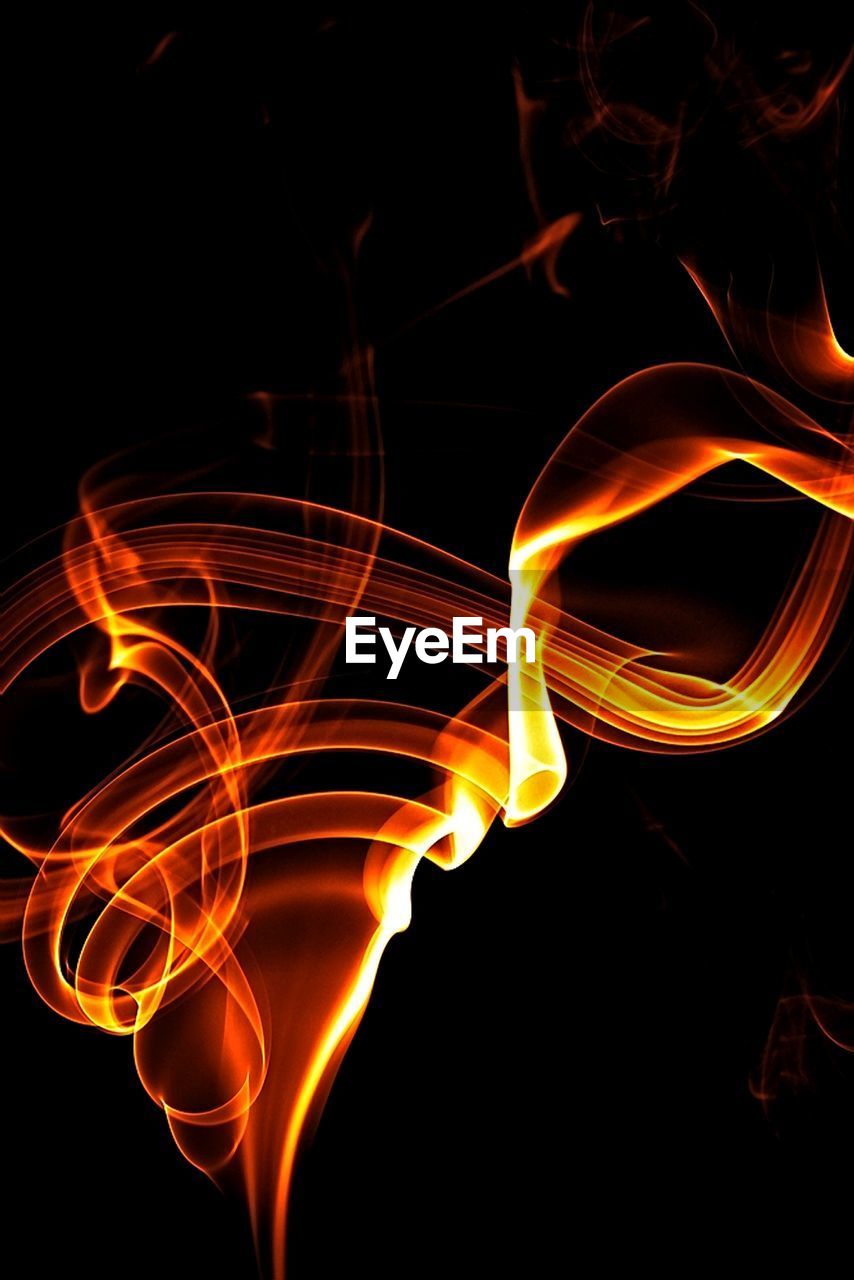 CLOSE-UP OF ILLUMINATED FIRE AGAINST BLACK BACKGROUND AT NIGHT