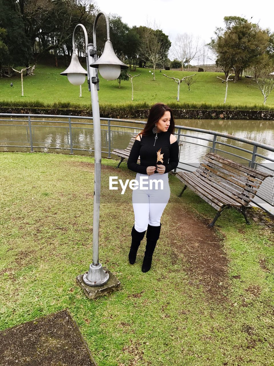 Full length of woman standing by lamp post at park