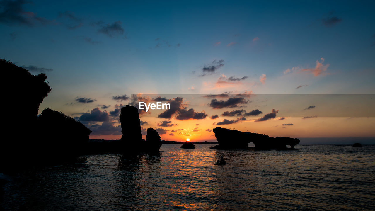 Silhouette boats in sea against sky during sunset