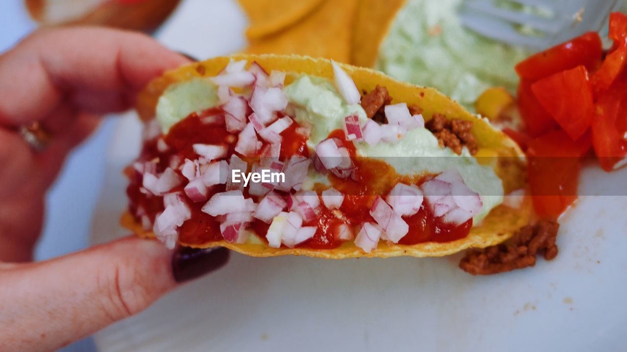 Cropped fingers of woman holding taco