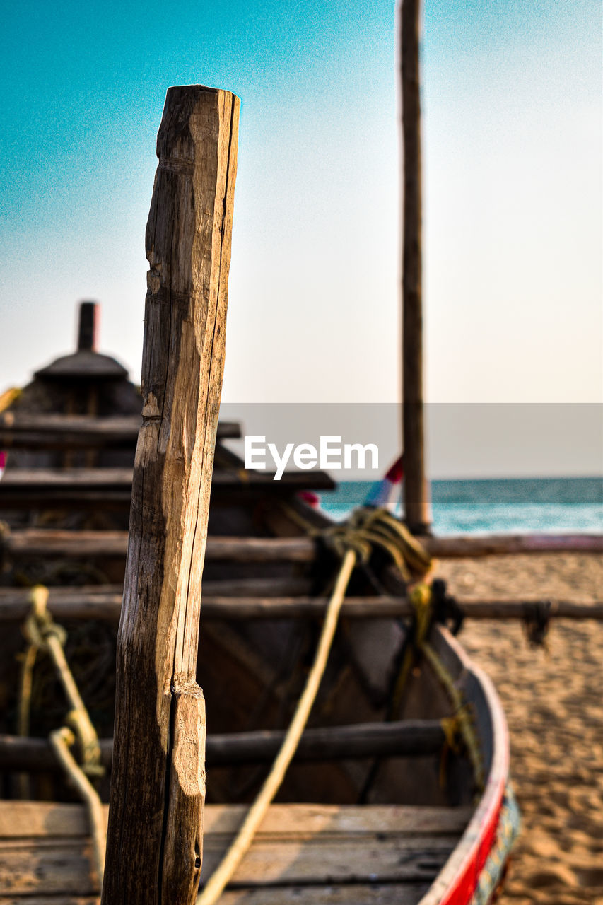 Close-up of wooden post on beach against clear sky