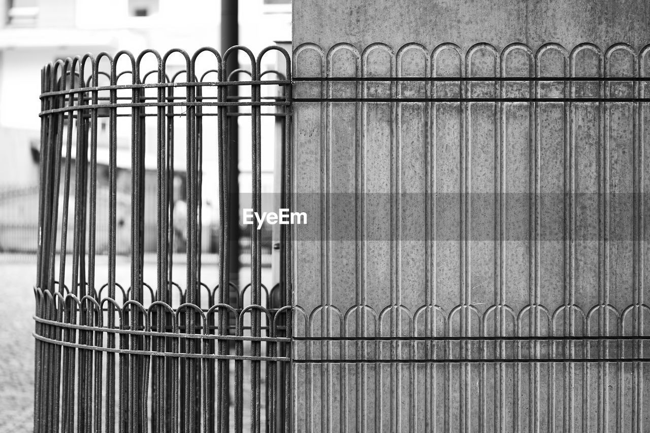 CLOSE-UP OF METAL FENCE AGAINST EMPTY WOODEN RAILING