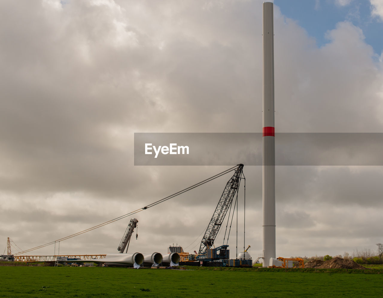 LOW ANGLE VIEW OF CRANES AT FIELD AGAINST SKY